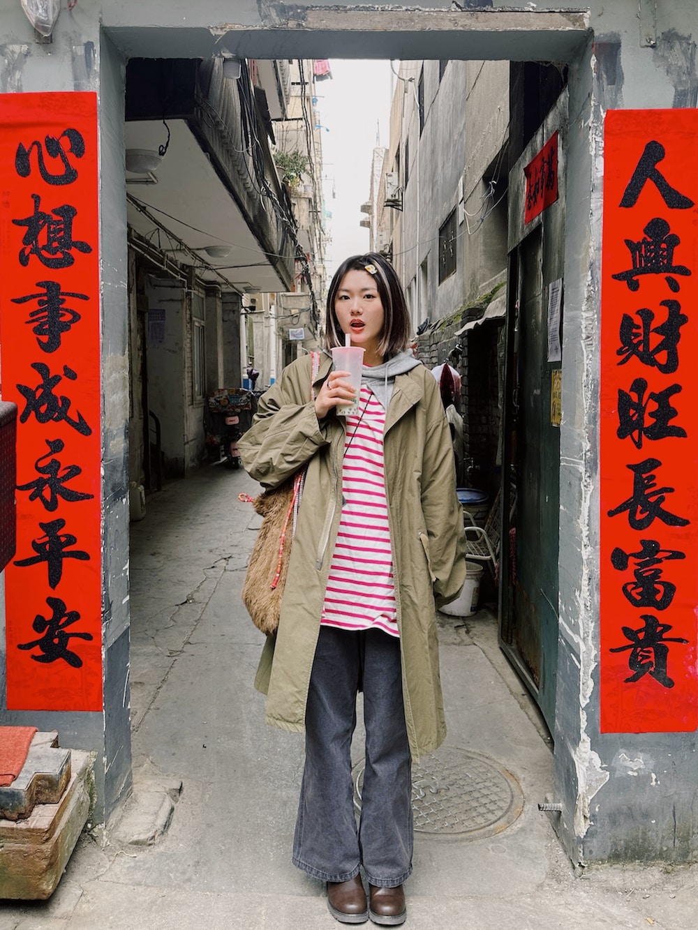 ブラウン系のショルダーバッグ、ブラック系のデニムパンツ、ブラウン系のブーツを着用したレディースの春コーディネートの2枚目の写真