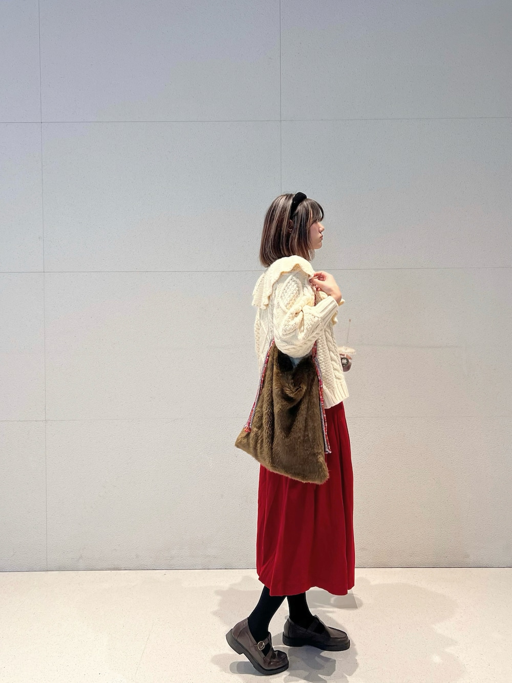 ホワイト系のニット/セーター、ブラウン系のショルダーバッグ、レッド系のスカートを着用したレディースの春コーディネートの2枚目の写真