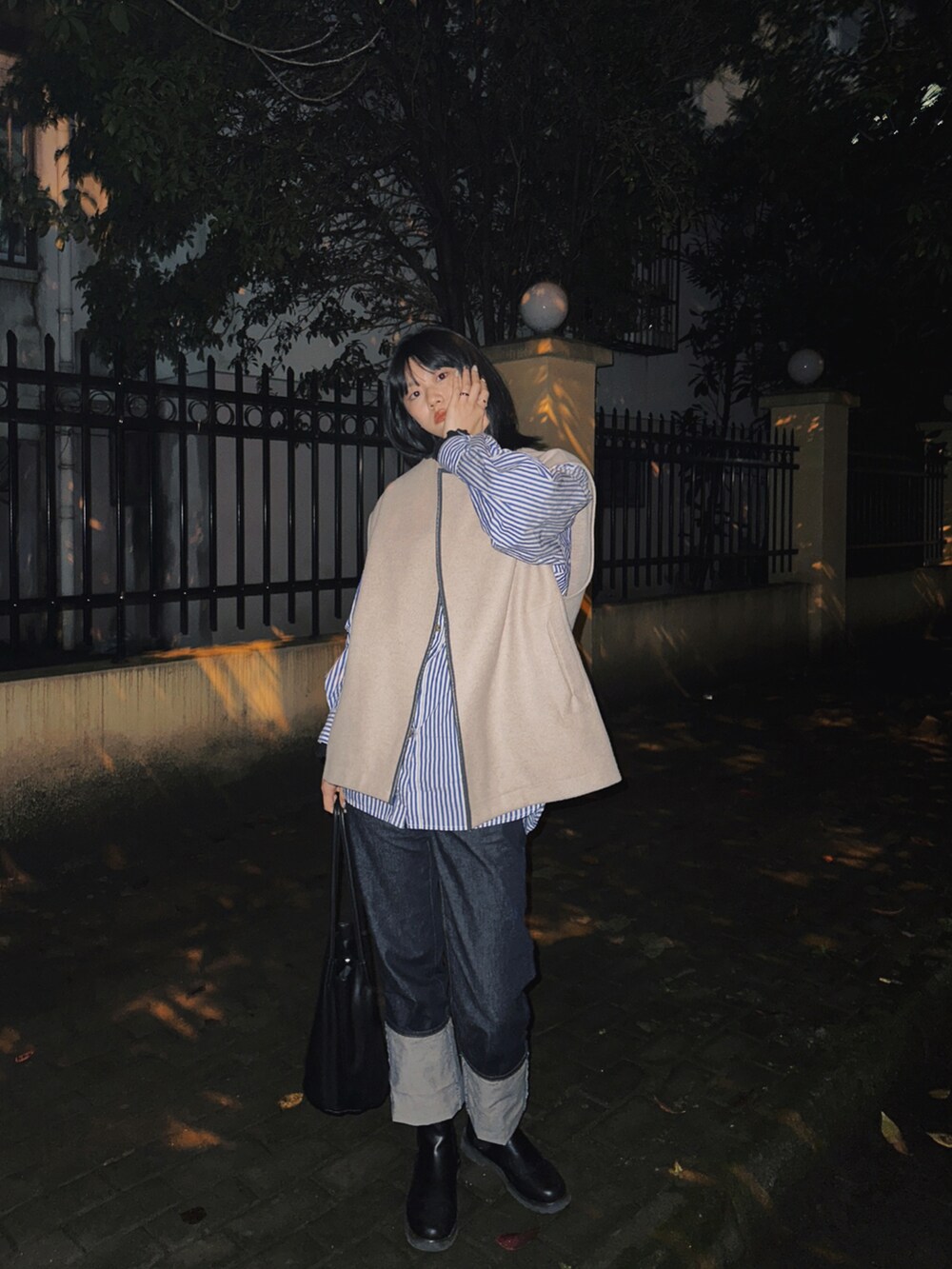 ベージュ系のベスト、グリーン系のノーカラーコート、ブラック系のトートバッグを着用したレディースの冬コーディネートの2枚目の写真