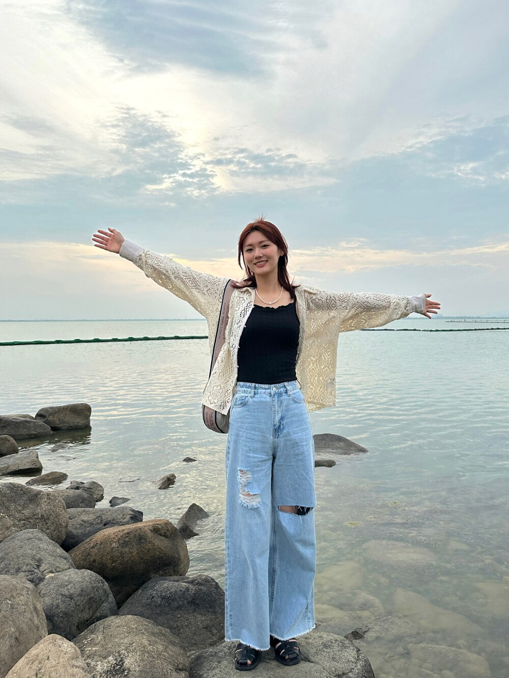 ブルー系のデニムパンツ、ホワイト系のシャツ/ブラウス、ブラック系のサンダルを着用したレディースの夏コーディネートの3枚目の写真