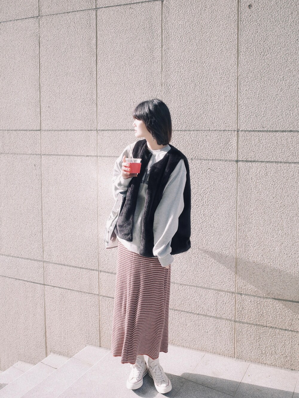 グレー系のスウェット、ブラック系のその他アウター、レッド系のスカートを着用したレディースの春コーディネートの2枚目の写真