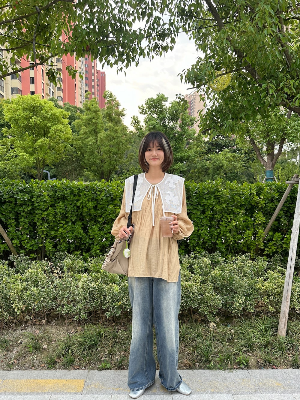 ブルー系のデニムパンツ、ホワイト系のシャツ/ブラウス、ベージュ系のショルダーバッグを着用したレディースの夏コーディネートの2枚目の写真