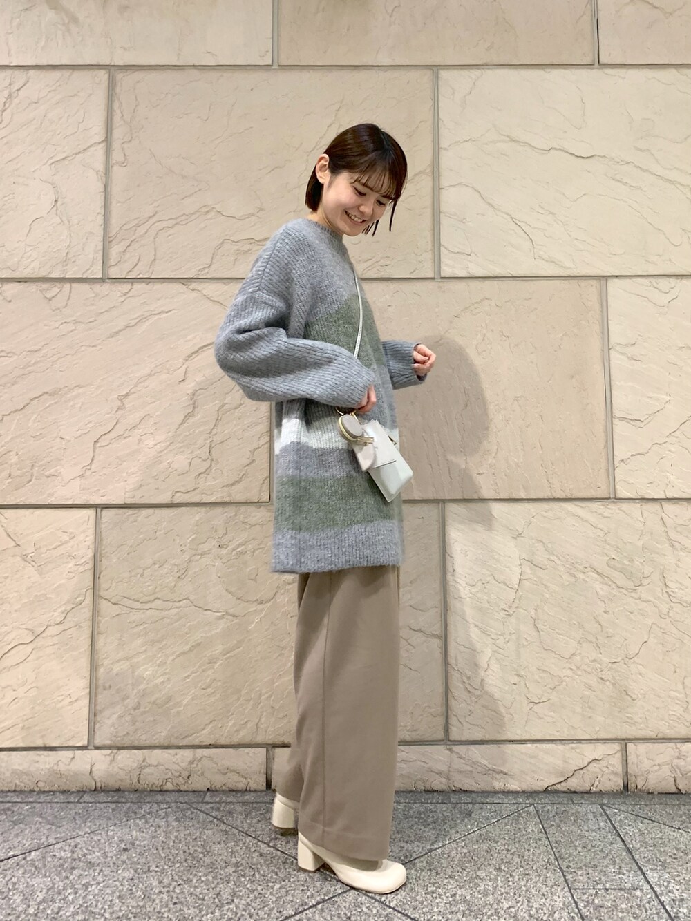 ブラウン系のその他パンツ、グレー系のニット/セーター、ベージュ系のショルダーバッグを着用したレディースの冬コーディネートの4枚目の写真