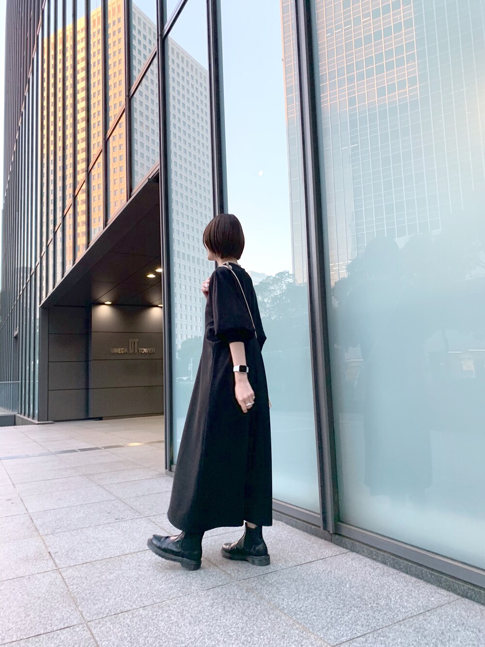 ブラック系のワンピース、ホワイト系のショルダーバッグ、ブラック系のブーツを着用したレディースの冬コーディネートの5枚目の写真