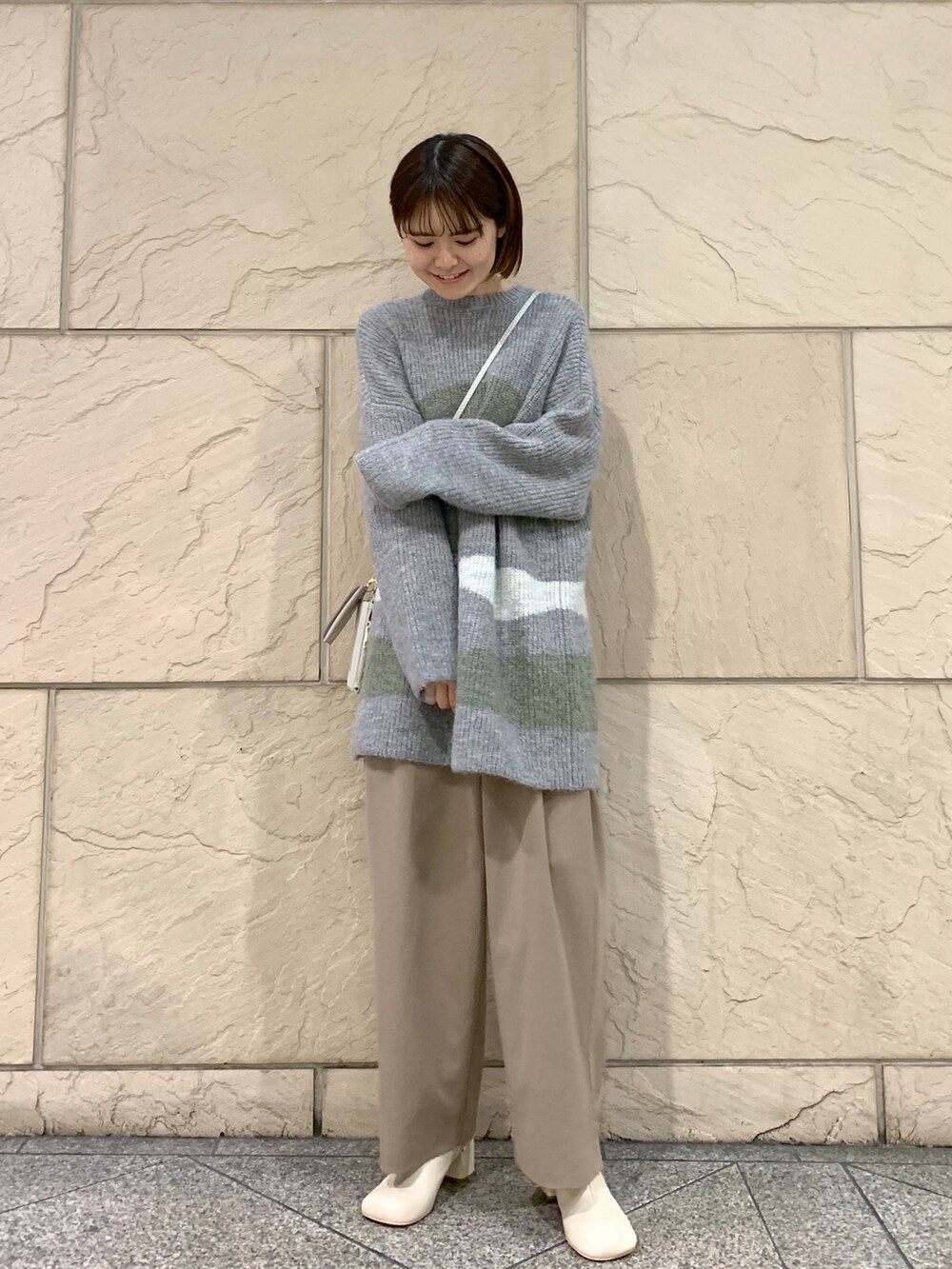 ブラウン系のその他パンツ、グレー系のニット/セーター、ベージュ系のショルダーバッグを着用したレディースの冬コーディネートの2枚目の写真