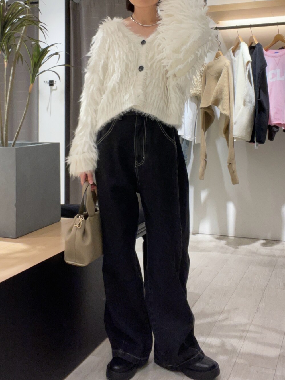 ホワイト系のカーディガン/ボレロ、ブラック系のデニムパンツ、ベージュ系のショルダーバッグを着用したレディースの秋コーディネートの2枚目の写真