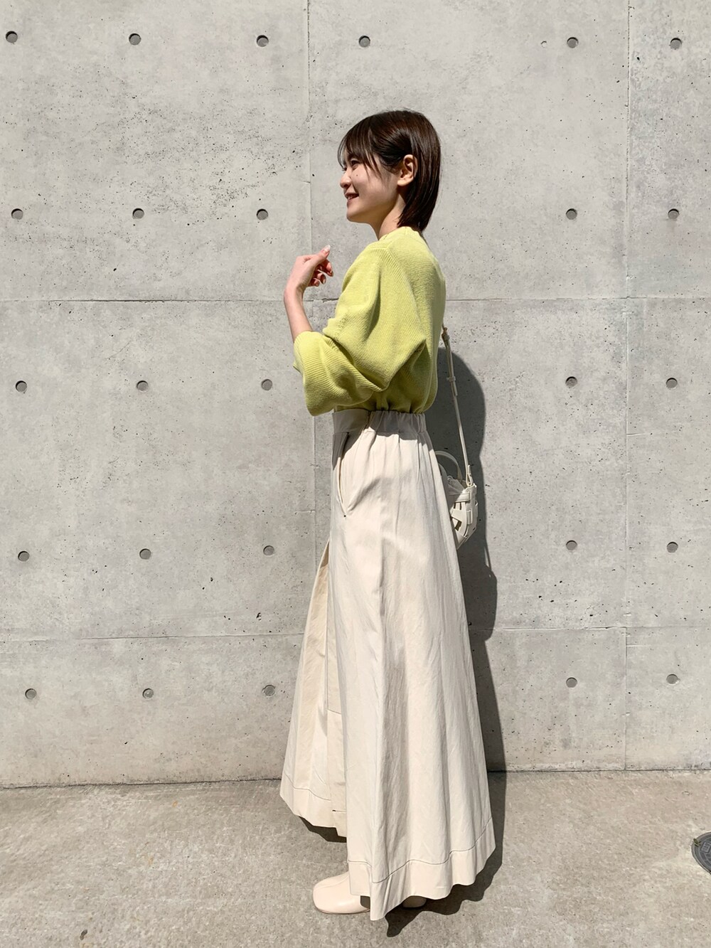 ホワイト系のスカート、イエロー系のニット/セーター、ホワイト系のショルダーバッグを着用したレディースの冬コーディネートの2枚目の写真