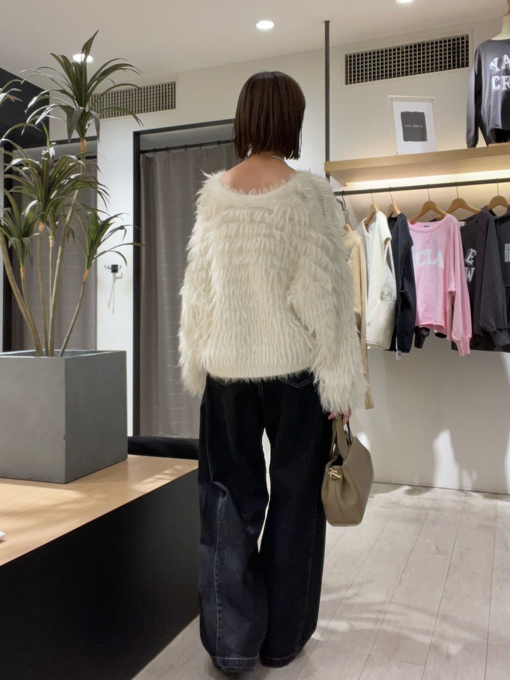 ホワイト系のカーディガン/ボレロ、ブラック系のデニムパンツ、ベージュ系のショルダーバッグを着用したレディースの秋コーディネートの4枚目の写真