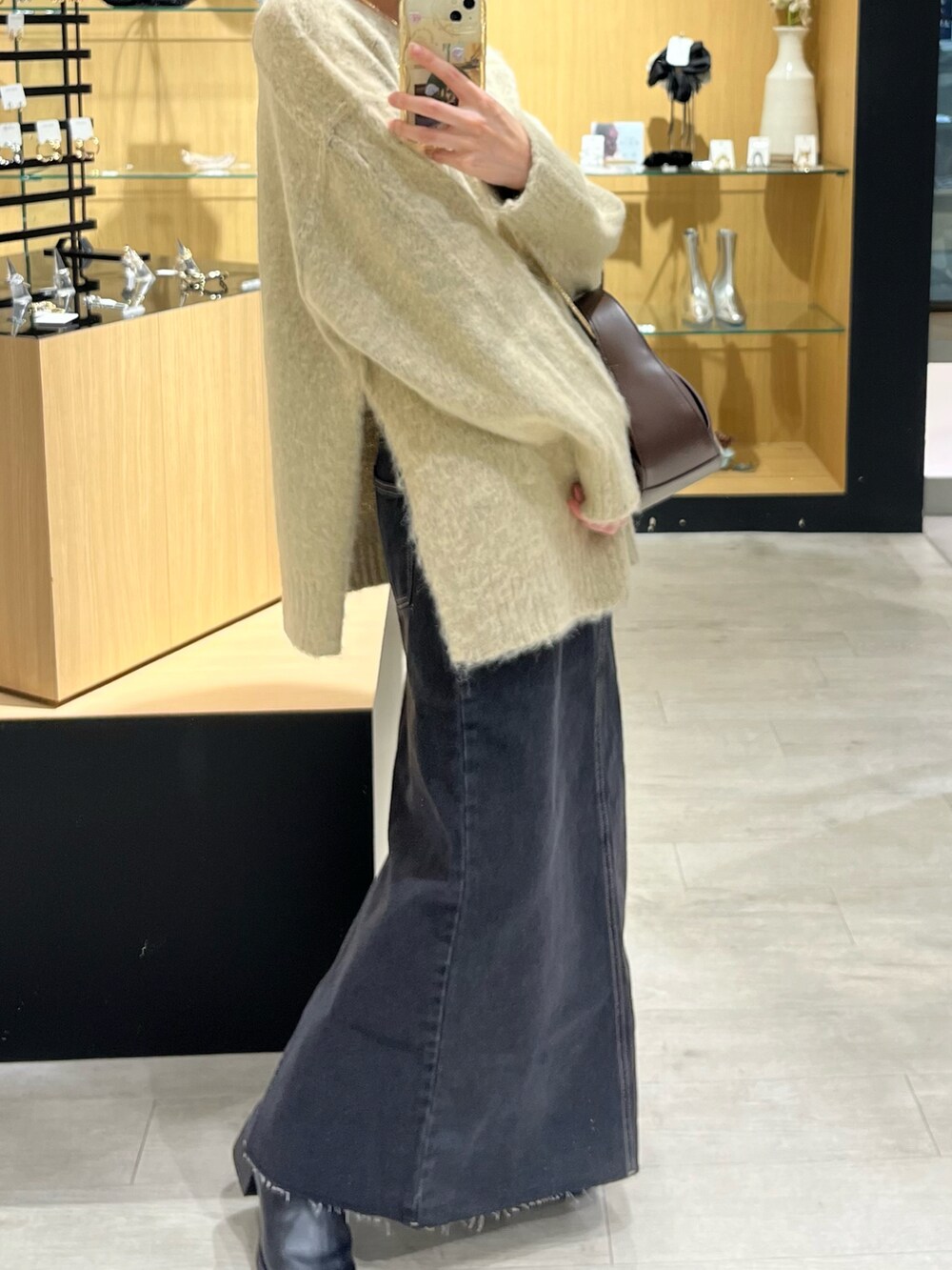 ベージュ系のニット/セーター、ブラック系のデニムスカート、ブラック系のブーツを着用したレディースの秋コーディネートの2枚目の写真