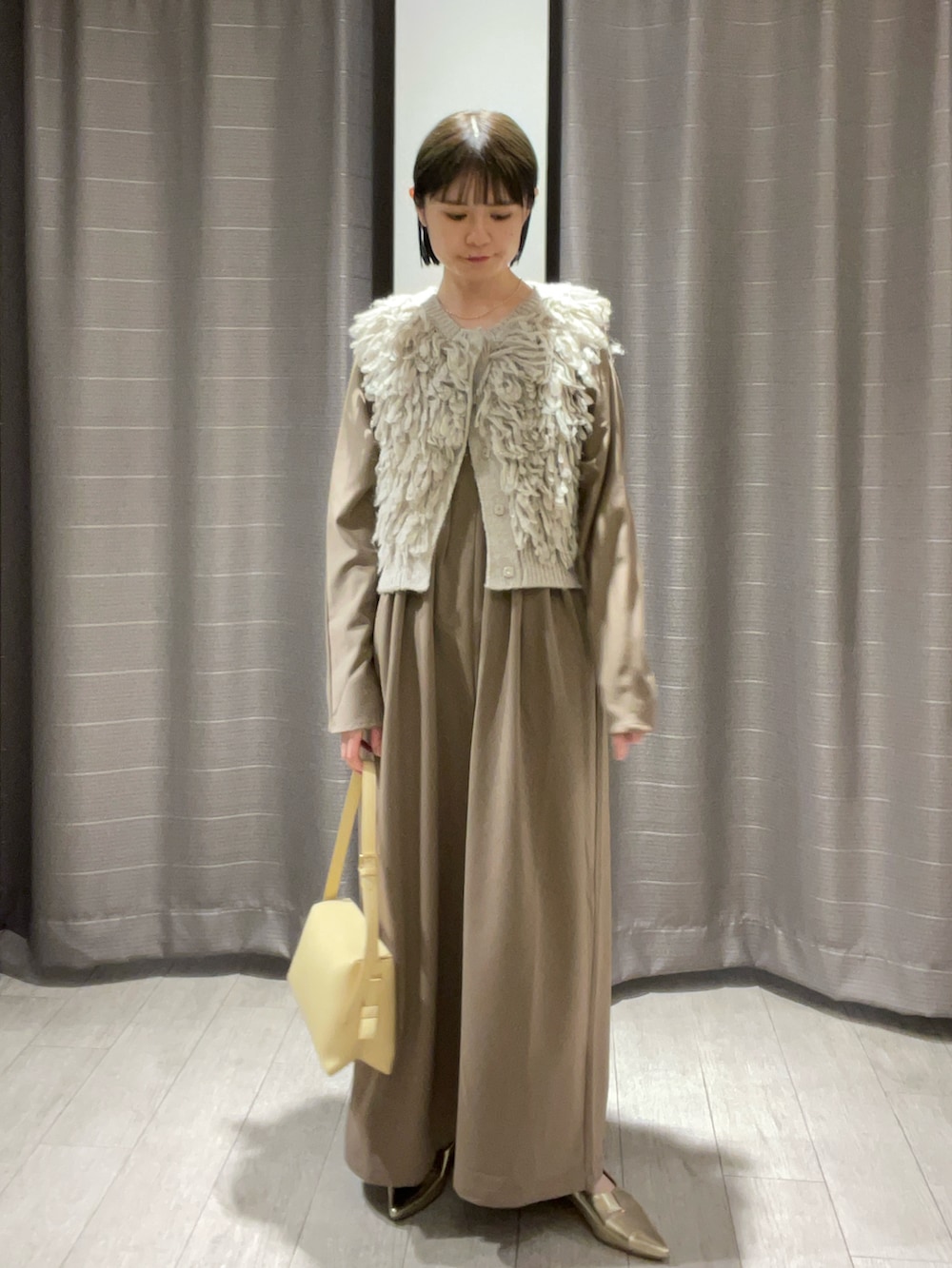 ベージュ系のショルダーバッグ、ゴールド系のパンプス、ブラウン系のワンピースを着用したレディースの秋コーディネートの4枚目の写真