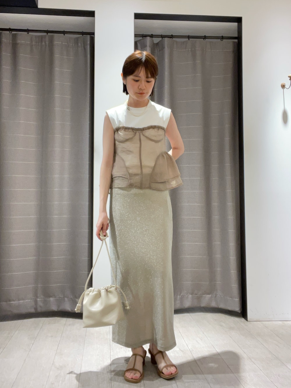 ベージュ系のTシャツ/カットソー、シルバー系のスカート、ホワイト系のバッグを着用したレディースの夏コーディネートの2枚目の写真