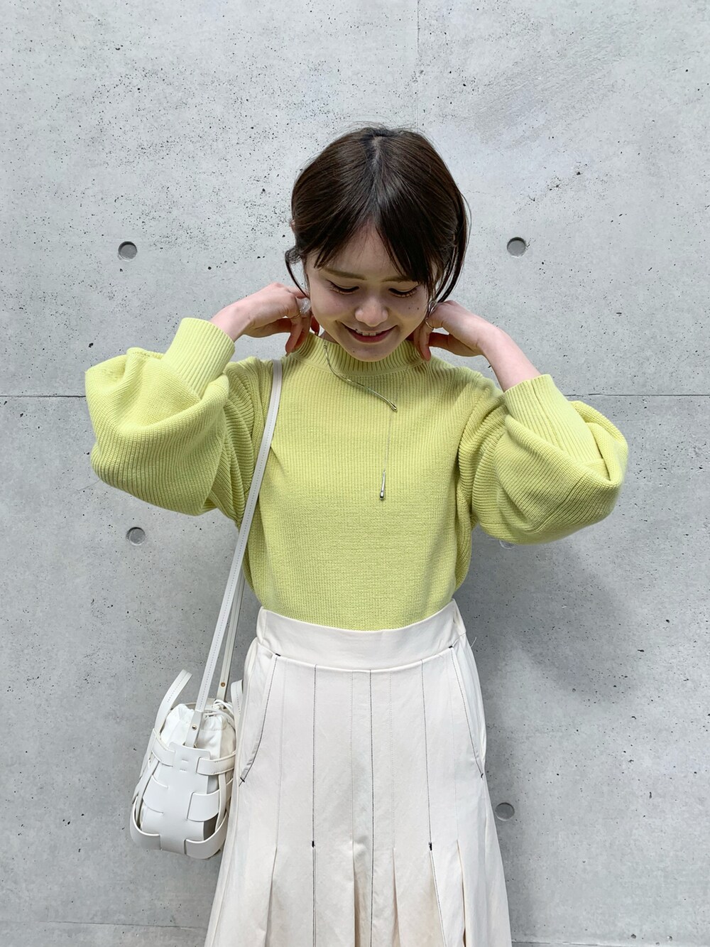 ホワイト系のスカート、イエロー系のニット/セーター、ホワイト系のショルダーバッグを着用したレディースの冬コーディネートの5枚目の写真