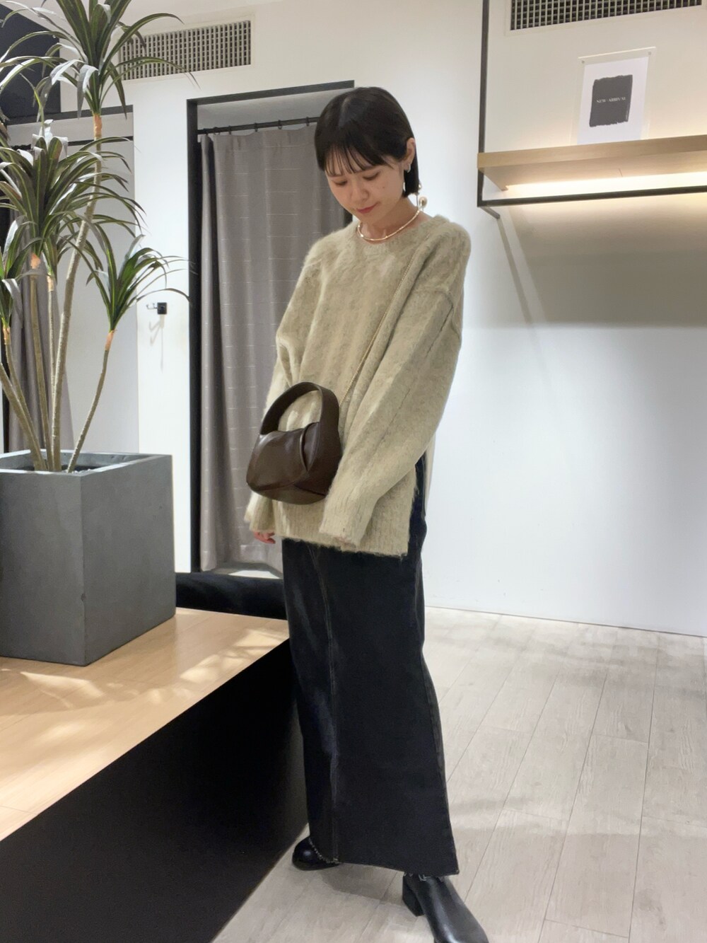 ベージュ系のニット/セーター、ブラック系のデニムスカート、ブラック系のブーツを着用したレディースの秋コーディネートの4枚目の写真