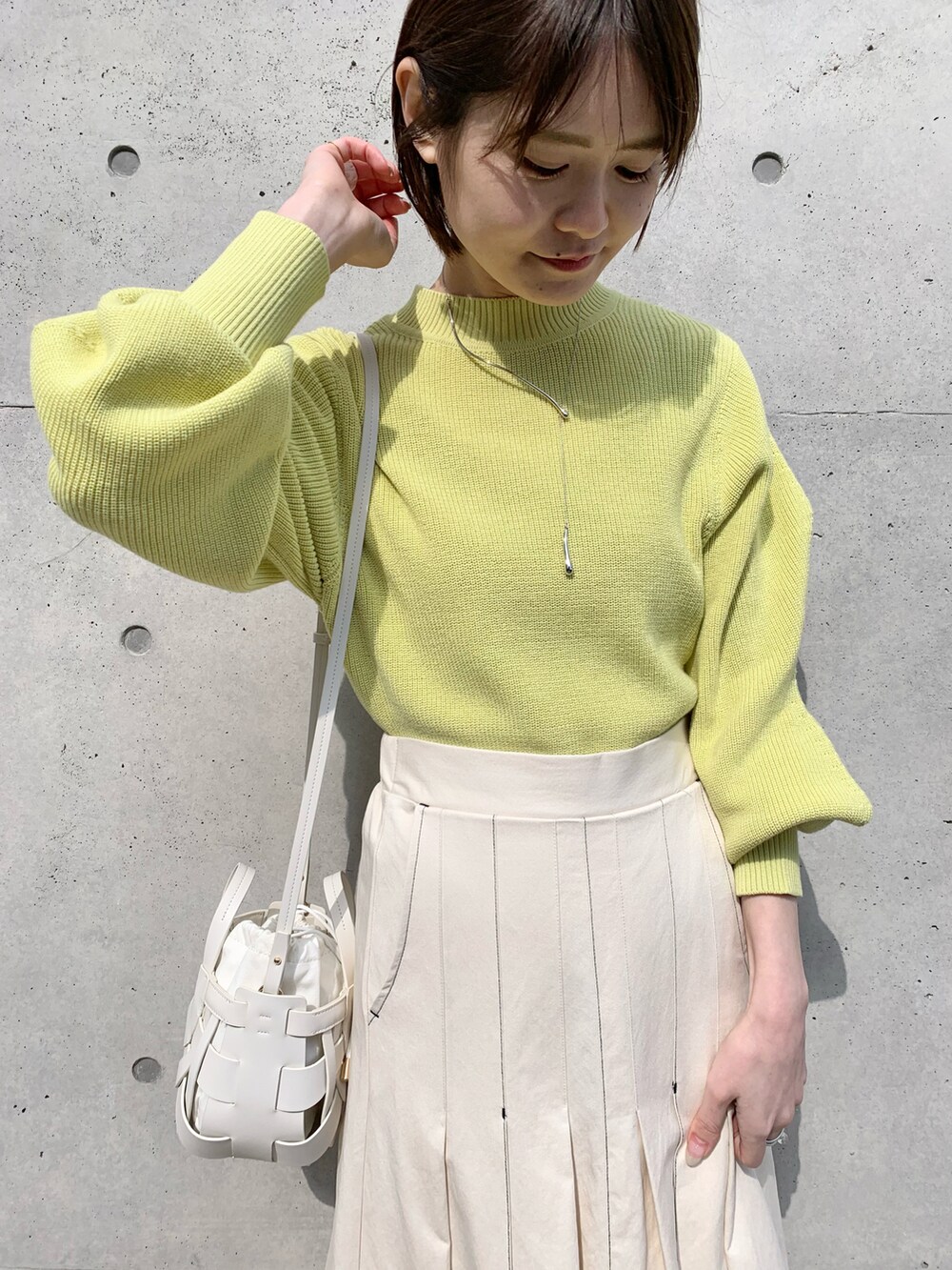 ホワイト系のスカート、イエロー系のニット/セーター、ホワイト系のショルダーバッグを着用したレディースの冬コーディネートの4枚目の写真