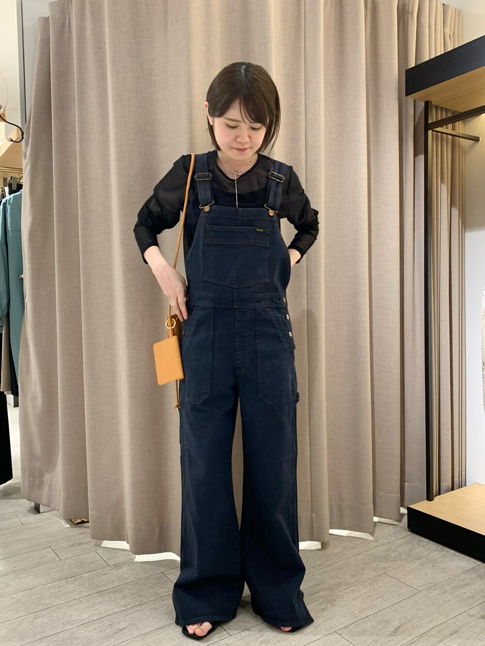 ブラック系のサロペット/オーバーオール、ブラック系のTシャツ/カットソー、ブラック系のサンダルを着用したレディースの春コーディネートの2枚目の写真