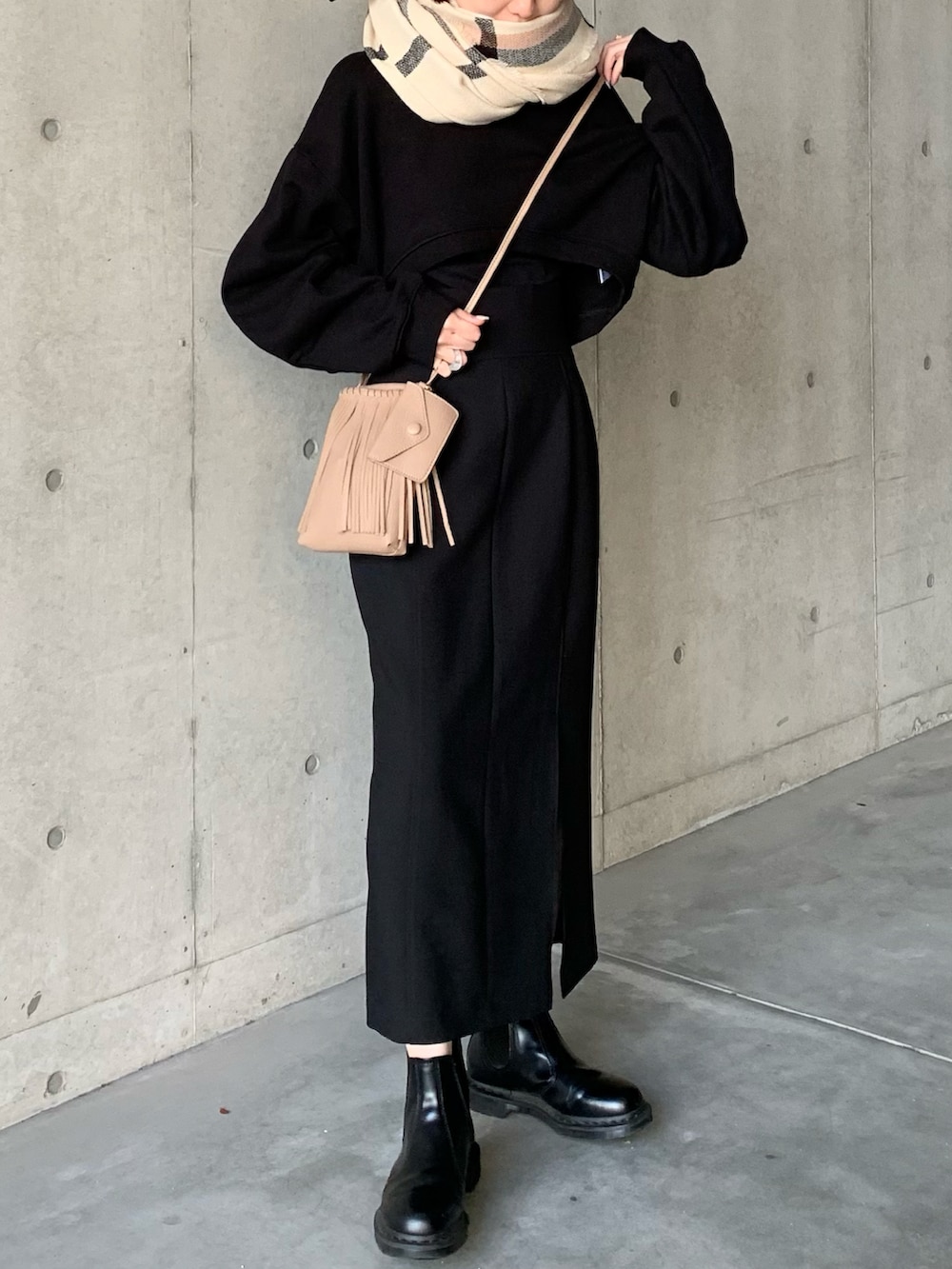 ブラック系のスカート、ブラック系のブーツ、ベージュ系のショルダーバッグを着用したレディースの冬コーディネートの2枚目の写真