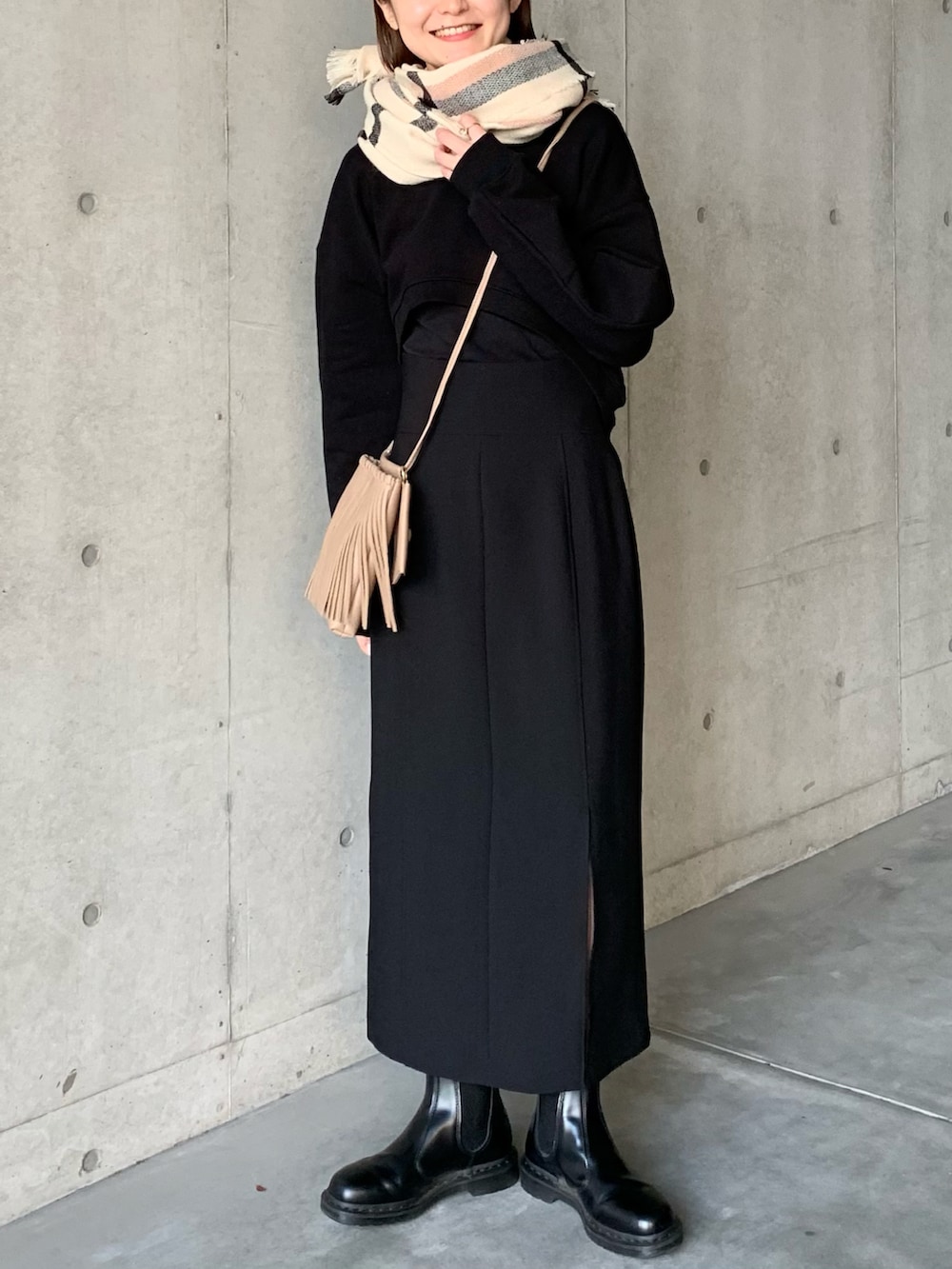 ブラック系のスカート、ブラック系のブーツ、ベージュ系のショルダーバッグを着用したレディースの冬コーディネートの5枚目の写真