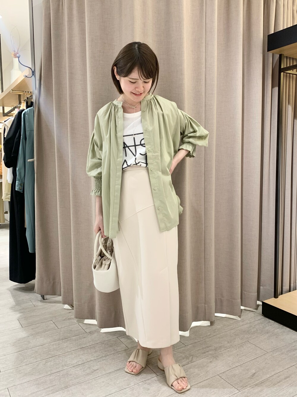 ホワイト系のサンダル、ベージュ系のスカート、ホワイト系のTシャツ/カットソーを着用したレディースの春コーディネートの2枚目の写真