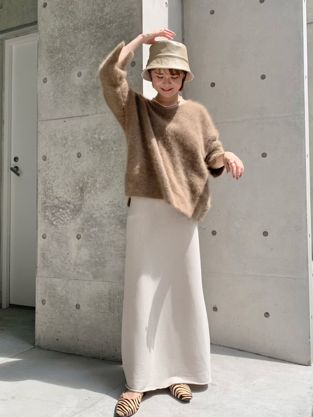 ブラウン系のニット/セーター、ホワイト系のスカート、ベージュ系のパンプスを着用したレディースの秋コーディネートの2枚目の写真