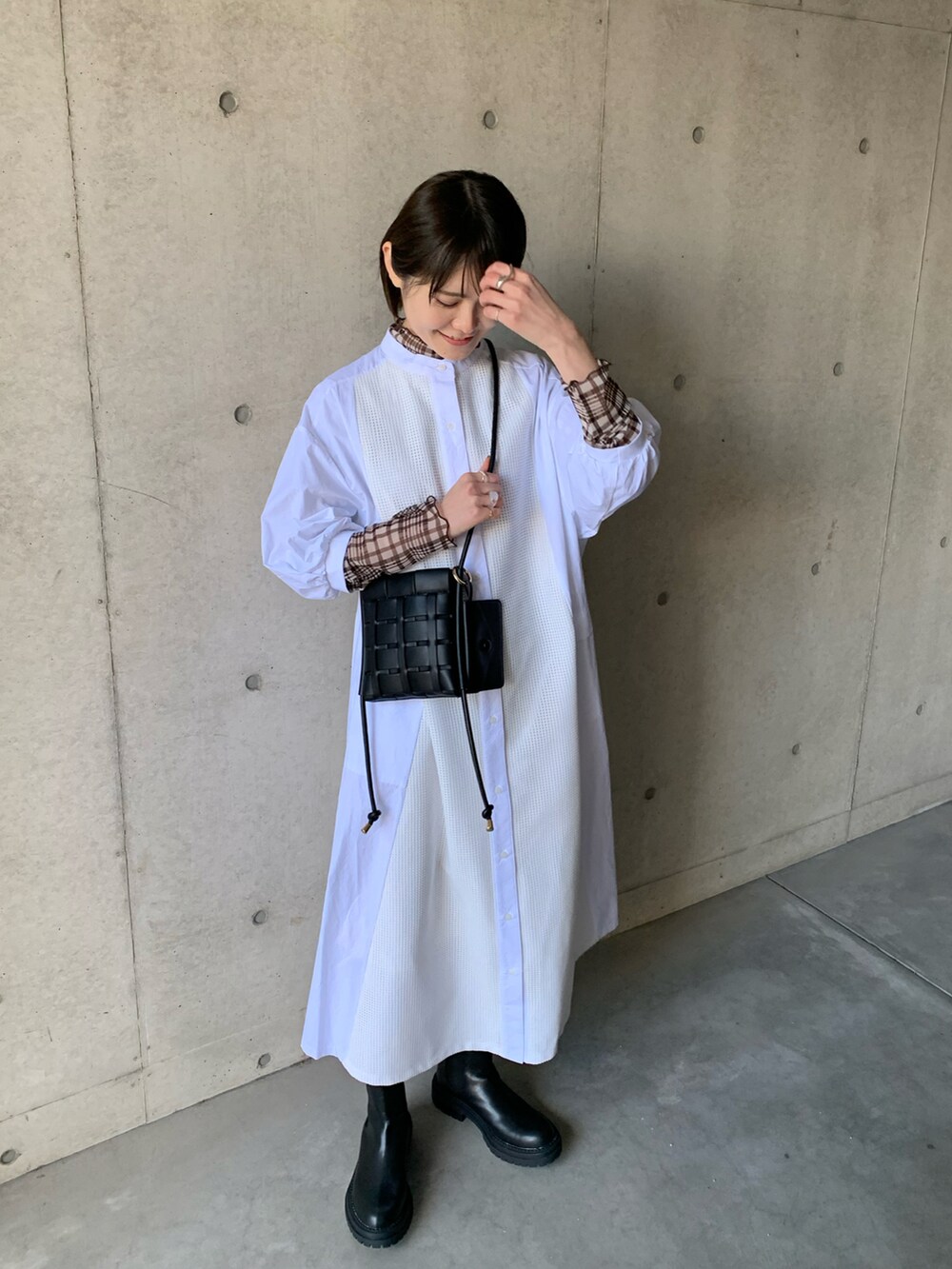 ホワイト系のシャツワンピース、ブラック系のブーツ、ブラウン系のTシャツ/カットソーを着用したレディースの冬コーディネートの5枚目の写真