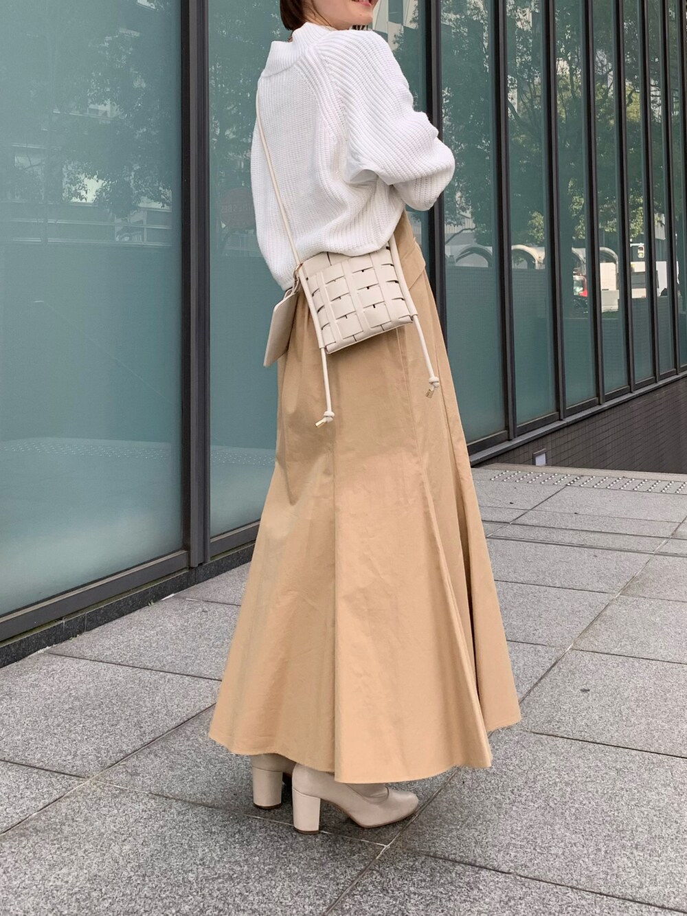 ホワイト系のブーツ、ベージュ系のスカート、ホワイト系のショルダーバッグを着用したレディースの冬コーディネートの2枚目の写真
