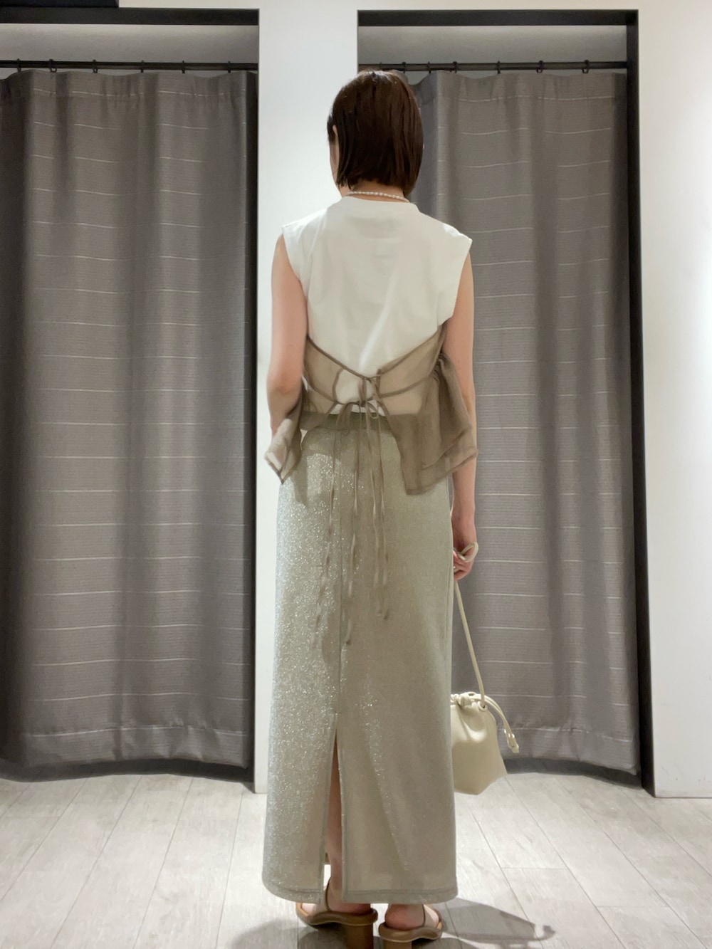 ベージュ系のTシャツ/カットソー、シルバー系のスカート、ホワイト系のバッグを着用したレディースの夏コーディネートの3枚目の写真