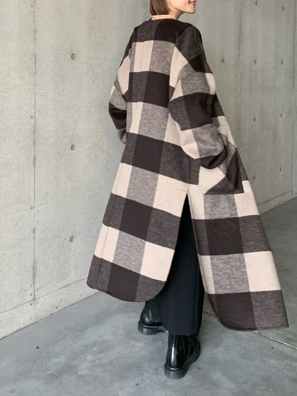 ブラック系のブーツ、ブラウン系のノーカラーコート、ブラック系のスカートを着用したレディースの秋コーディネートの4枚目の写真