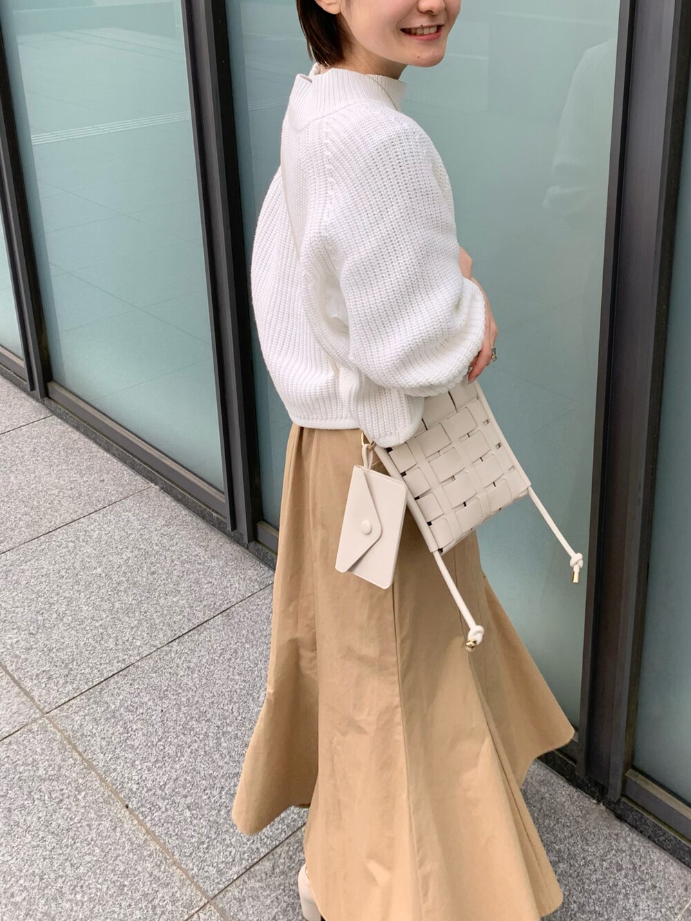 ホワイト系のブーツ、ベージュ系のスカート、ホワイト系のショルダーバッグを着用したレディースの冬コーディネートの3枚目の写真