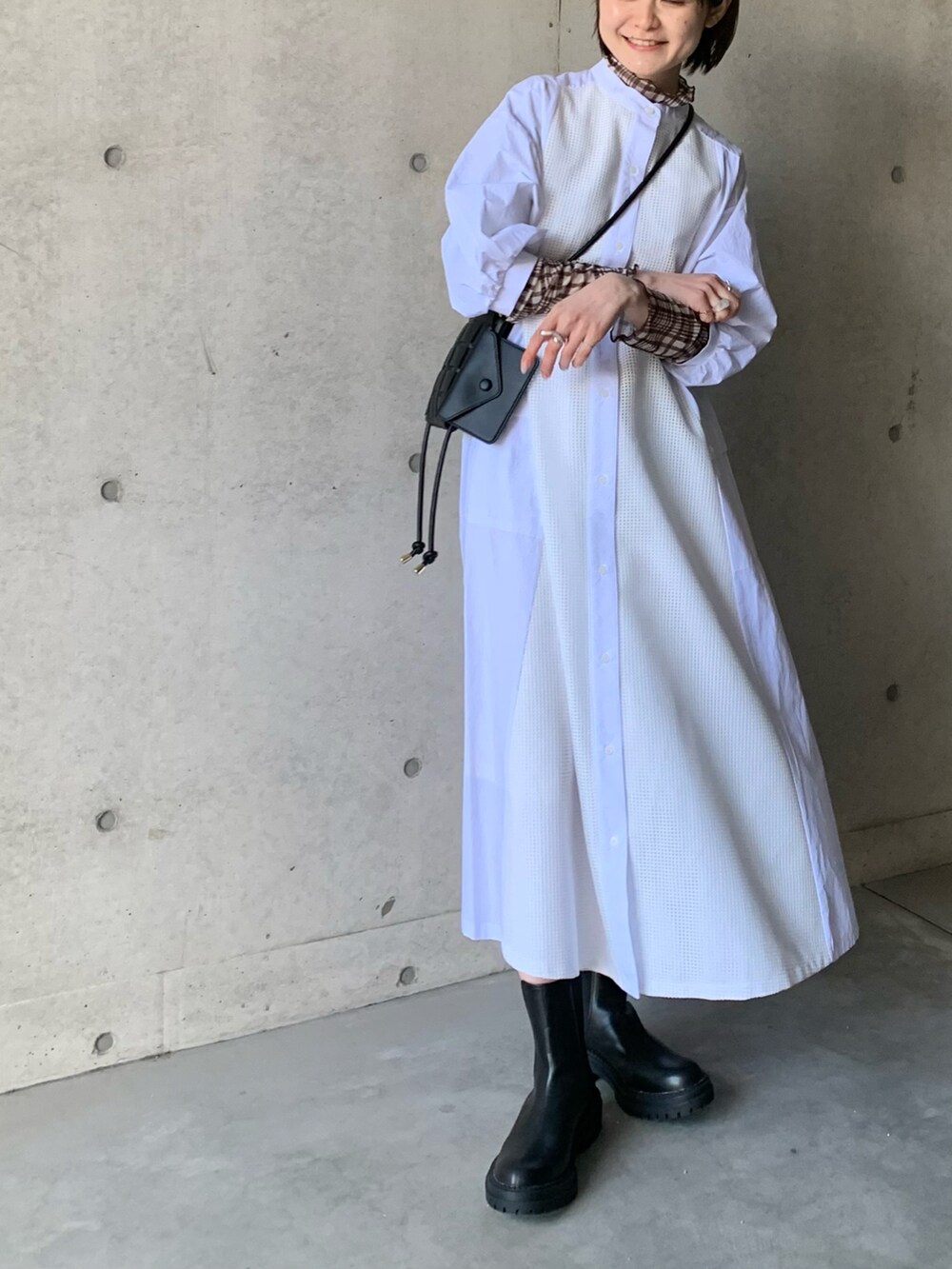 ホワイト系のシャツワンピース、ブラック系のブーツ、ブラウン系のTシャツ/カットソーを着用したレディースの冬コーディネートの4枚目の写真