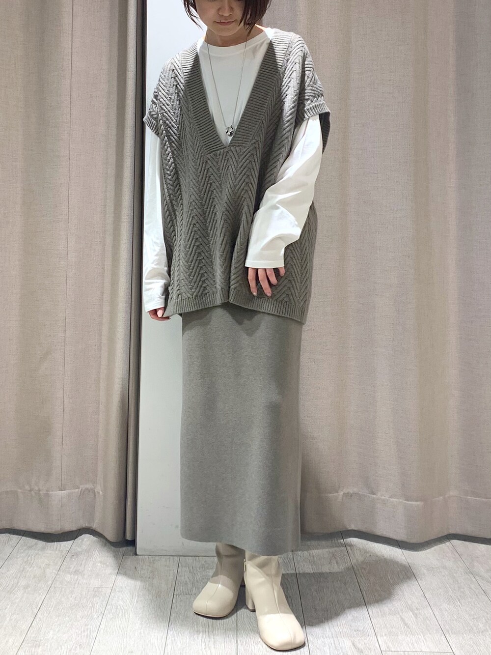 ベージュ系のワンピース、ホワイト系のブーツ、シルバー系のネックレスを着用したレディースの冬コーディネートの2枚目の写真