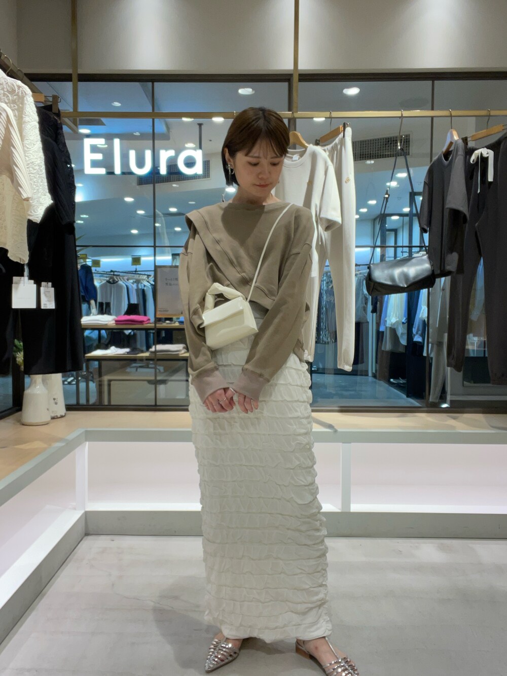 ブラウン系のTシャツ/カットソー、ホワイト系のスカート、シルバー系のサンダルを着用したレディースの秋コーディネートの2枚目の写真