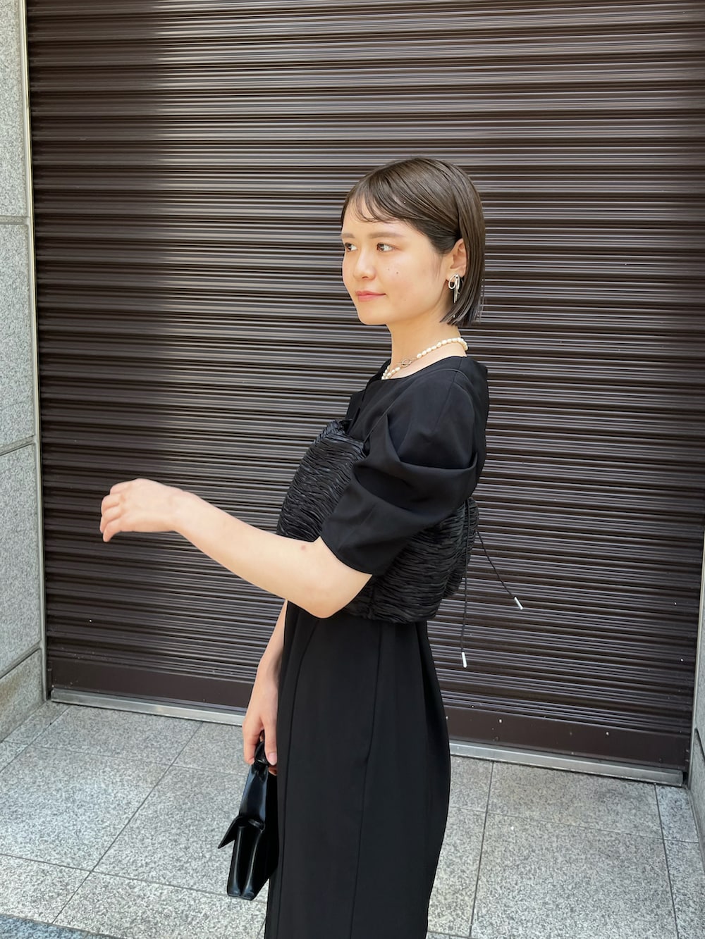 ブラック系のワンピース、ブラック系のパンプス、ブラック系のバッグを着用したレディースの夏コーディネートの5枚目の写真