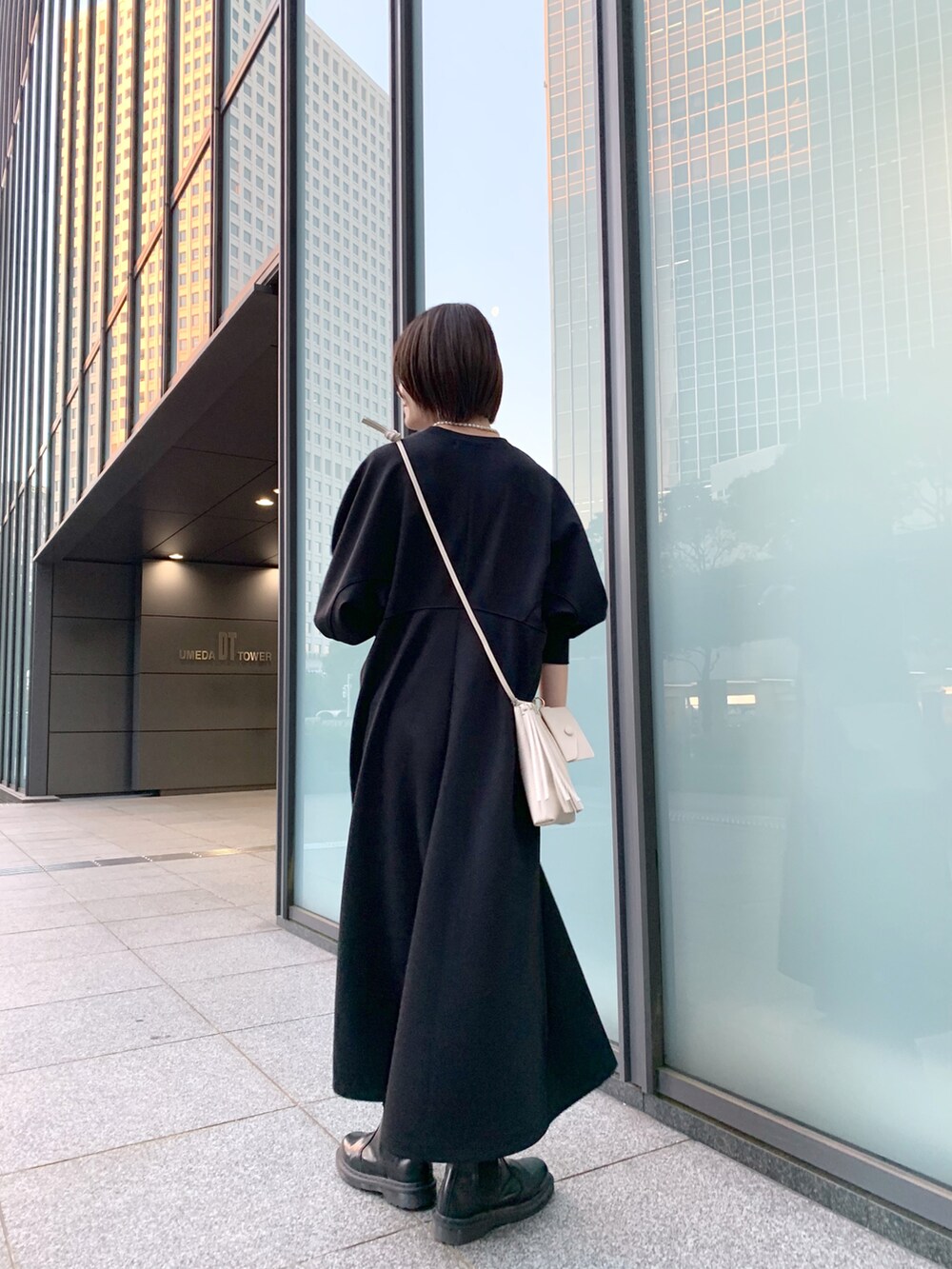 ブラック系のワンピース、ホワイト系のショルダーバッグ、ブラック系のブーツを着用したレディースの冬コーディネートの4枚目の写真