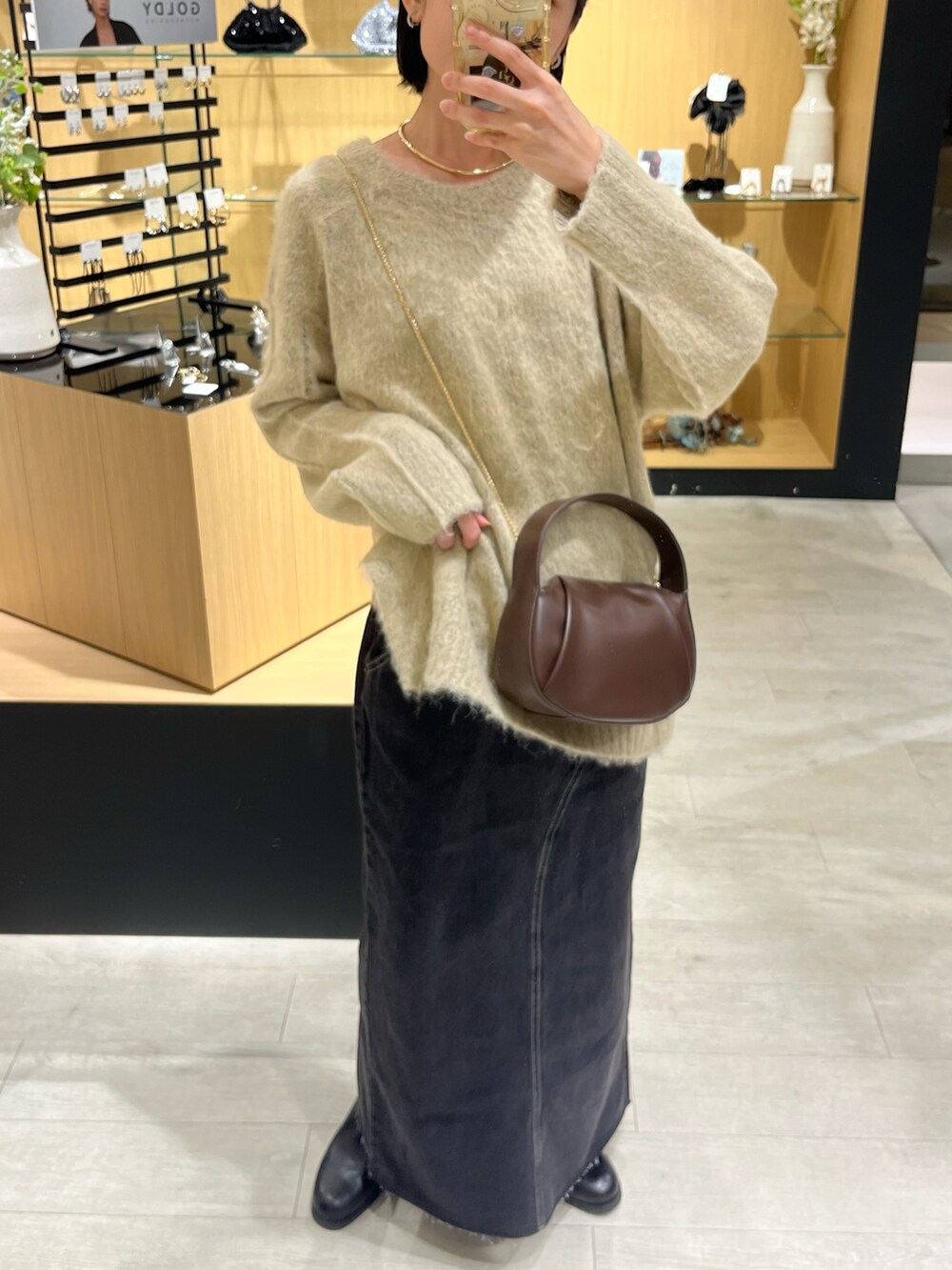 ベージュ系のニット/セーター、ブラック系のデニムスカート、ブラック系のブーツを着用したレディースの秋コーディネートの3枚目の写真