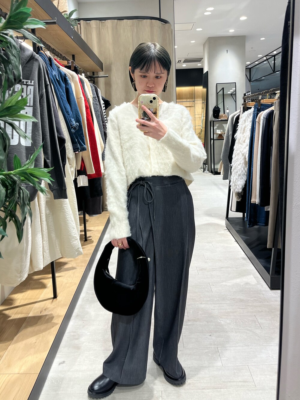 ブラック系のショルダーバッグ、ホワイト系のカーディガン/ボレロ、ブラック系のその他パンツを着用したレディースの冬コーディネートの2枚目の写真