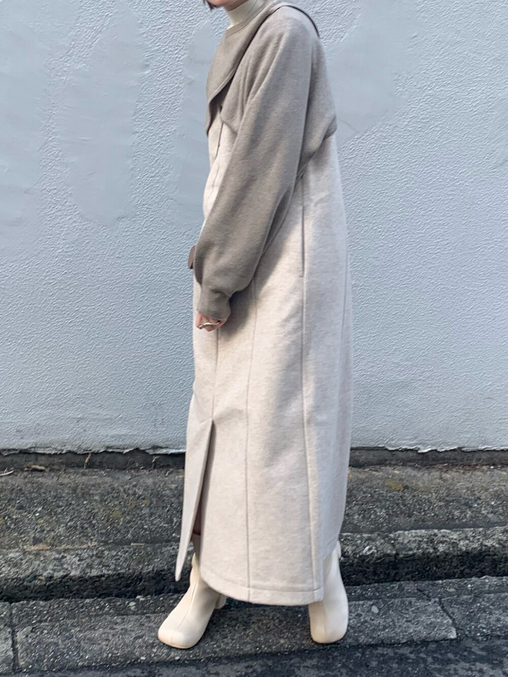 ホワイト系のブーツ、ブラック系のワンピース、ベージュ系のニット/セーターを着用したレディースの冬コーディネートの2枚目の写真