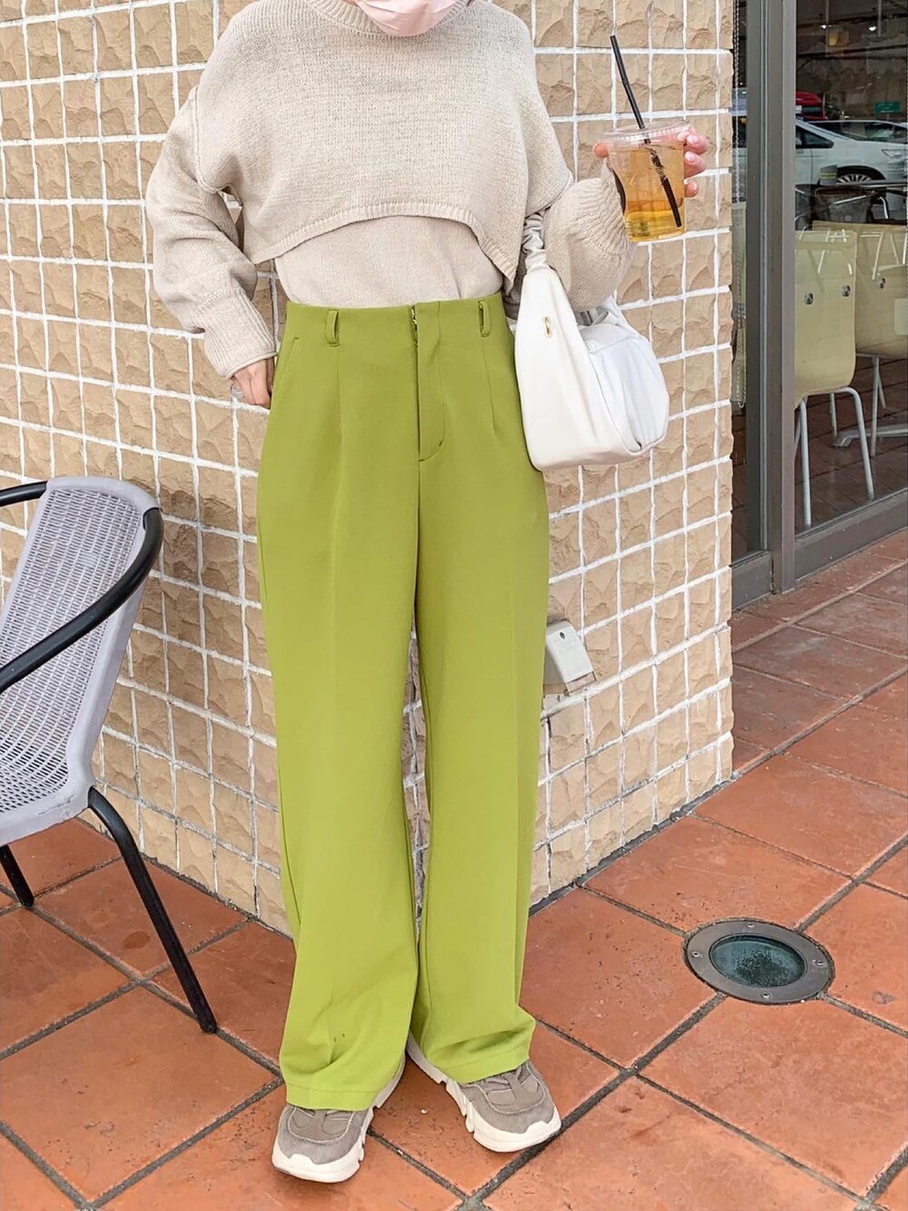 グリーン系のスラックス、ベージュ系のスニーカー、ホワイト系のハンドバッグを着用したレディースの冬コーディネートの2枚目の写真