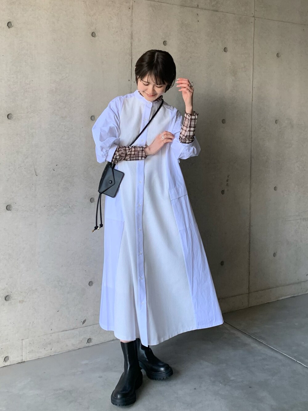 ホワイト系のシャツワンピース、ブラック系のブーツ、ブラウン系のTシャツ/カットソーを着用したレディースの冬コーディネートの2枚目の写真