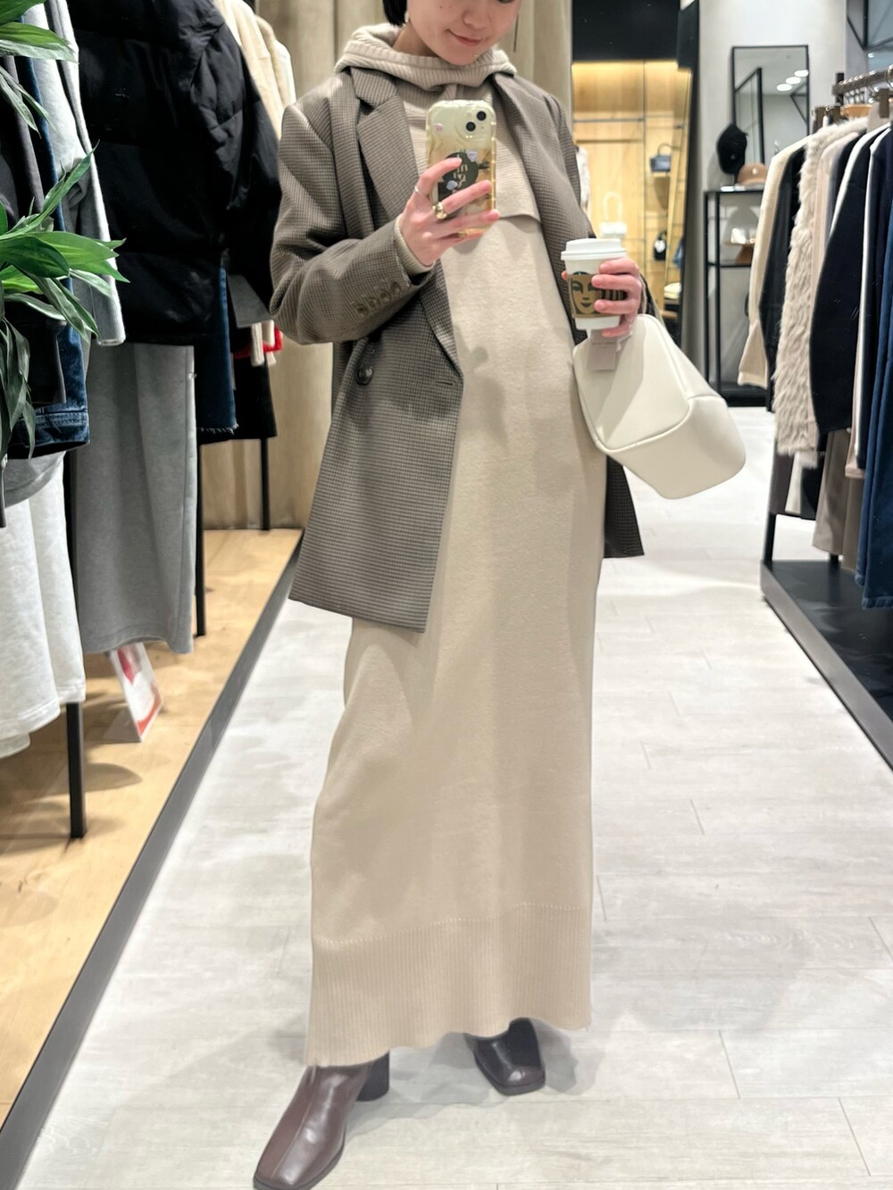 ブラウン系のブーツ、ベージュ系のワンピース、ホワイト系のハンドバッグを着用したレディースの冬コーディネートの4枚目の写真