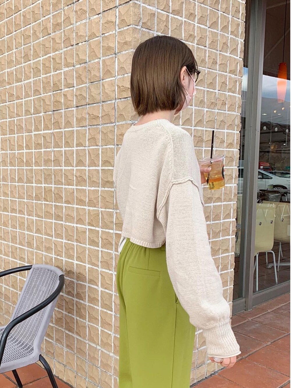 グリーン系のスラックス、ベージュ系のスニーカー、ホワイト系のハンドバッグを着用したレディースの冬コーディネートの3枚目の写真