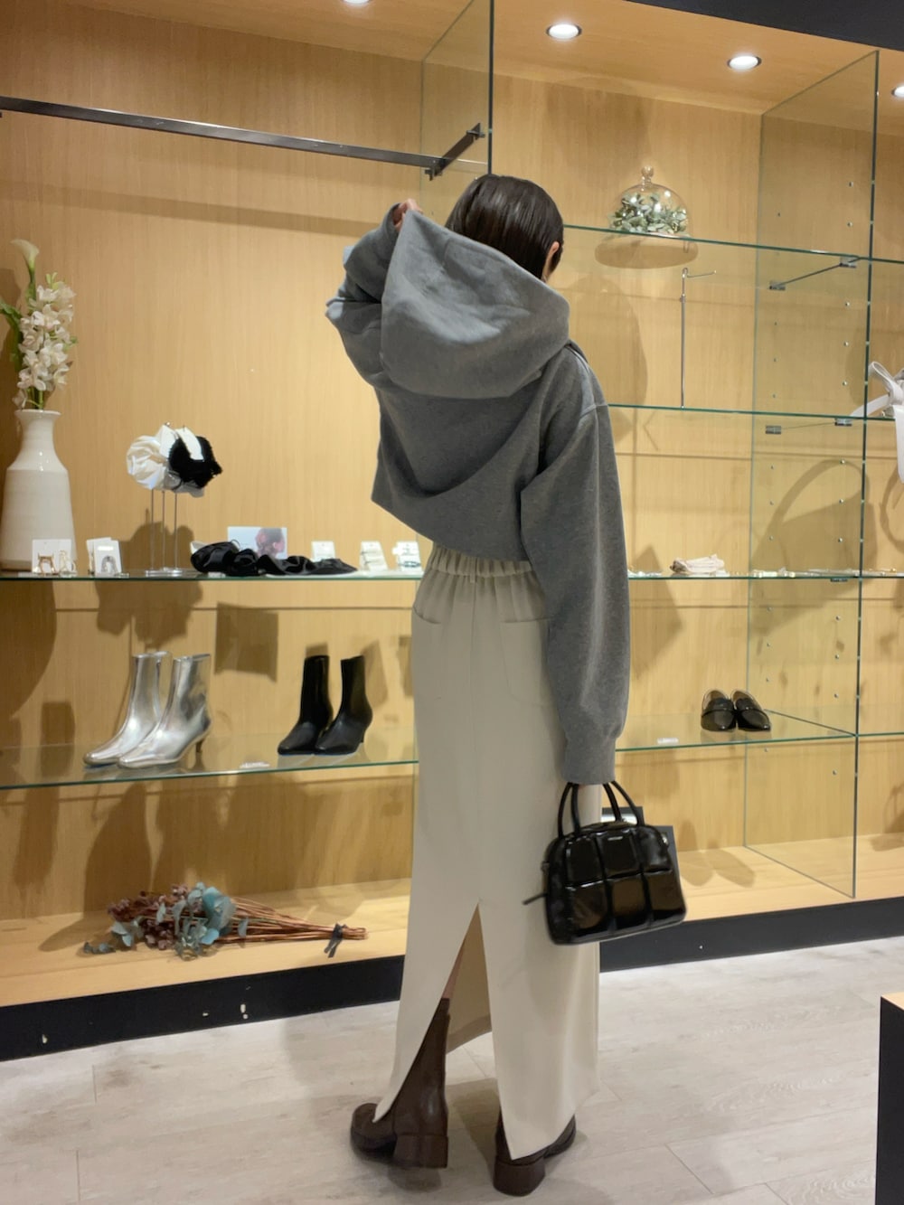 グレー系のパーカー、ホワイト系のスカート、ブラック系のバッグを着用したレディースの秋コーディネートの3枚目の写真