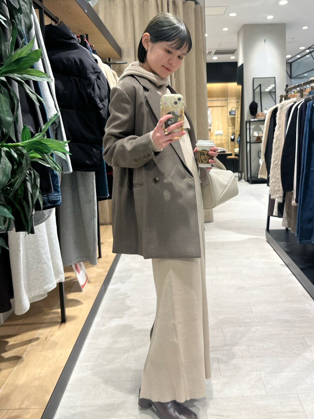 ブラウン系のブーツ、ベージュ系のワンピース、ホワイト系のハンドバッグを着用したレディースの冬コーディネートの2枚目の写真