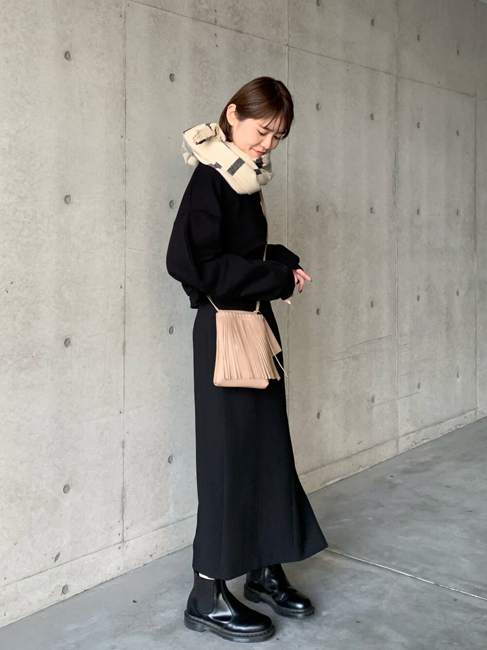ブラック系のスカート、ブラック系のブーツ、ベージュ系のショルダーバッグを着用したレディースの冬コーディネートの4枚目の写真