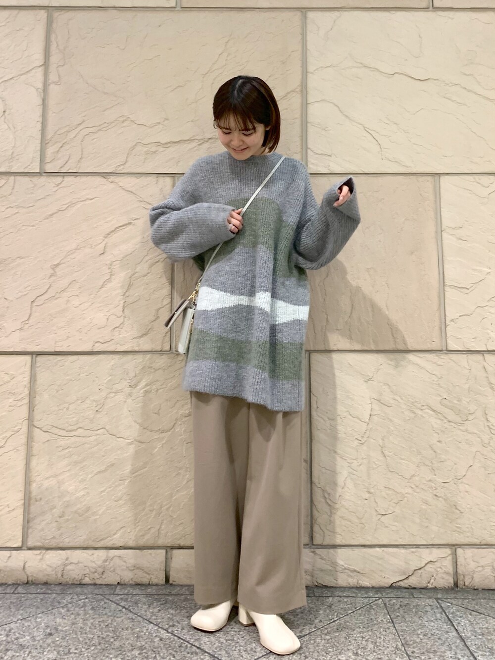 ブラウン系のその他パンツ、グレー系のニット/セーター、ベージュ系のショルダーバッグを着用したレディースの冬コーディネートの3枚目の写真
