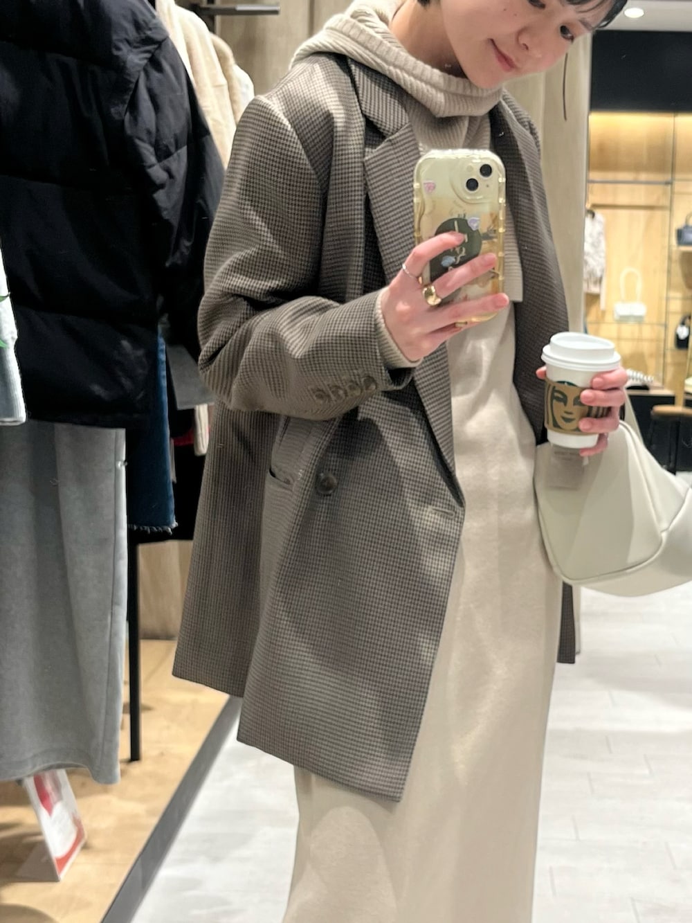 ブラウン系のブーツ、ベージュ系のワンピース、ホワイト系のハンドバッグを着用したレディースの冬コーディネートの3枚目の写真