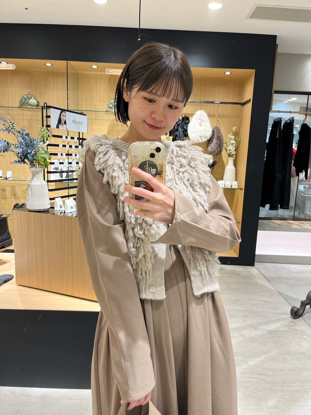 ベージュ系のショルダーバッグ、ゴールド系のパンプス、ブラウン系のワンピースを着用したレディースの秋コーディネートの2枚目の写真