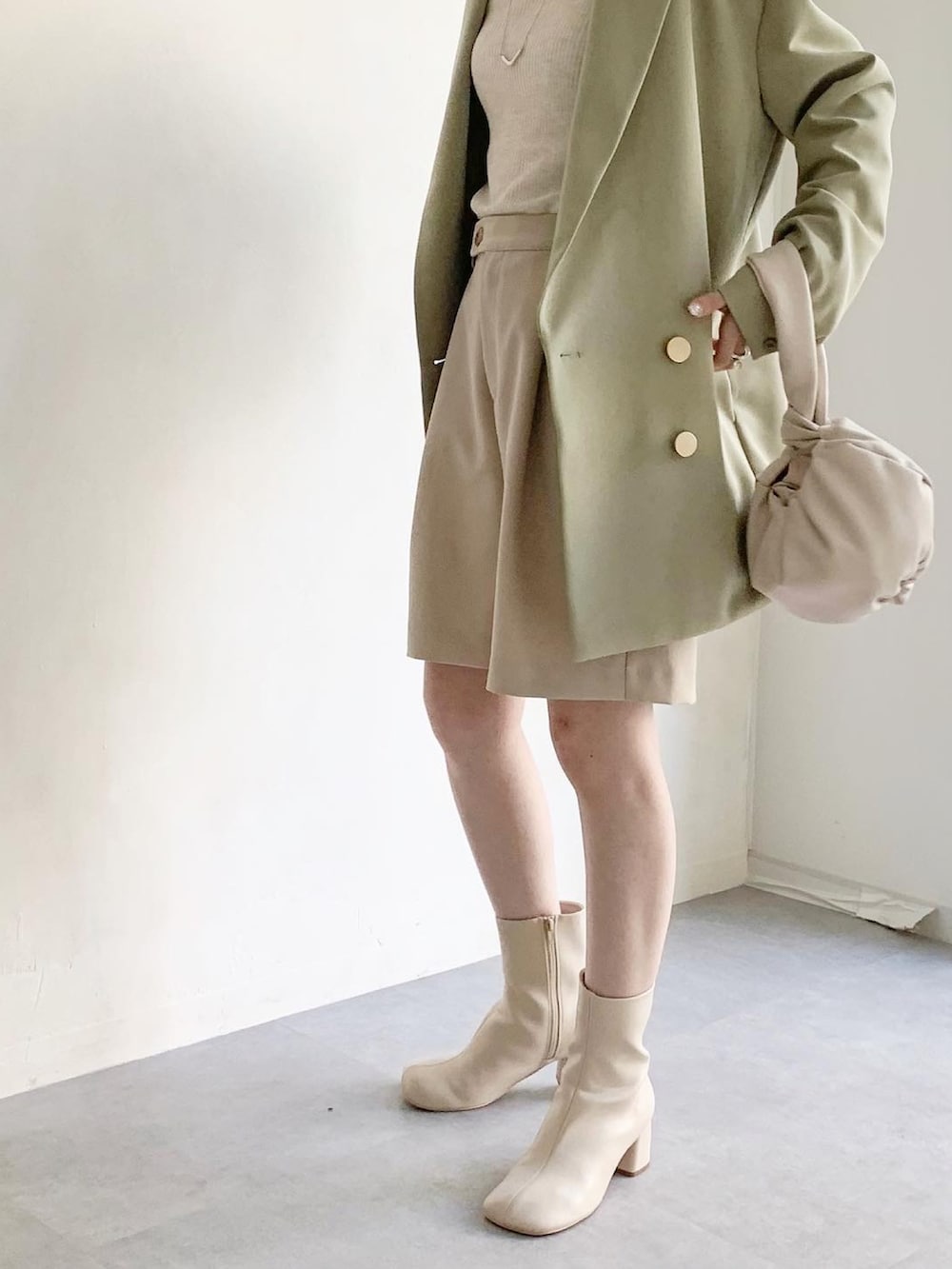 グリーン系のテーラードジャケット、ベージュ系のニット/セーター、ホワイト系のハンドバッグを着用したレディースの春コーディネートの3枚目の写真