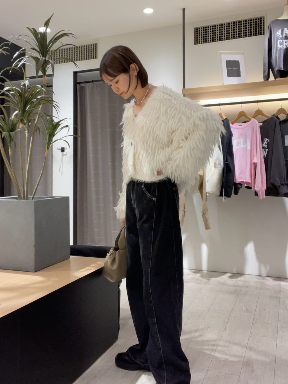 ホワイト系のカーディガン/ボレロ、ブラック系のデニムパンツ、ベージュ系のショルダーバッグを着用したレディースの秋コーディネートの3枚目の写真