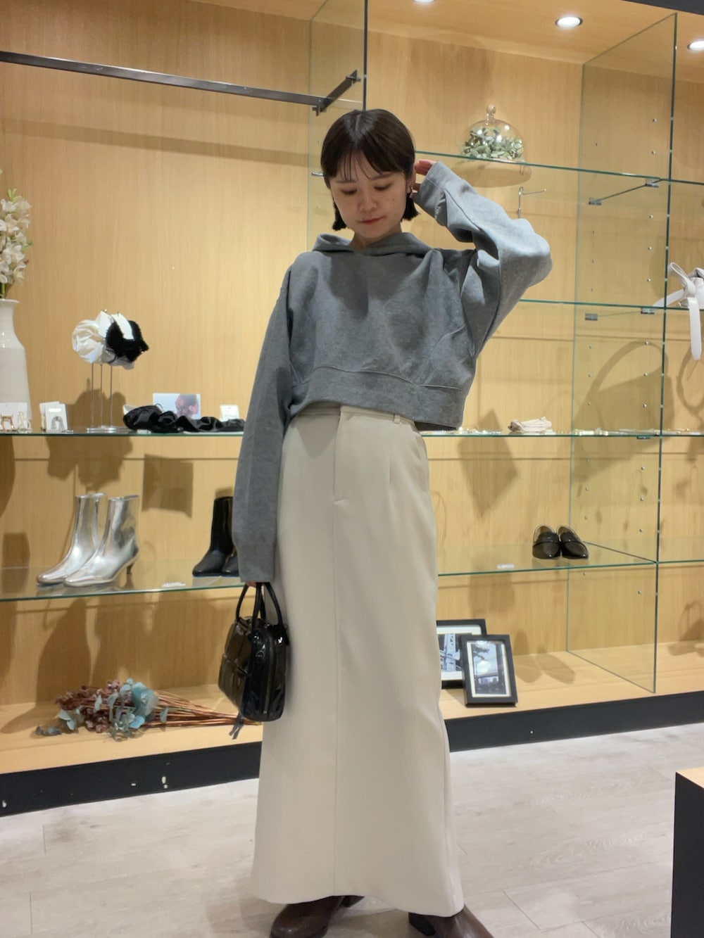 グレー系のパーカー、ホワイト系のスカート、ブラック系のバッグを着用したレディースの秋コーディネートの4枚目の写真