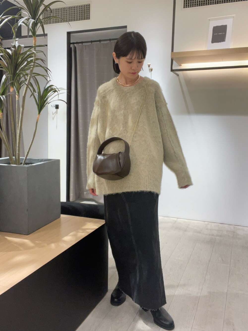 ベージュ系のニット/セーター、ブラック系のデニムスカート、ブラック系のブーツを着用したレディースの秋コーディネートの5枚目の写真